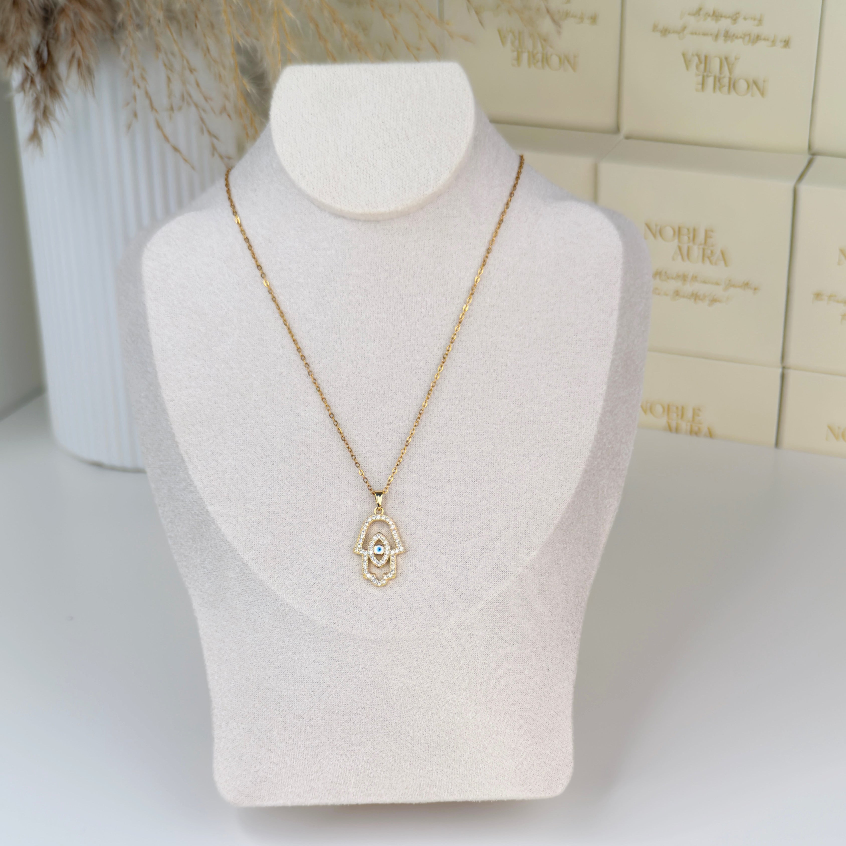 Gold Hamsa hand necklace with evil eye crystal pavé detailing by Noble Aura UK. Nazar Necklace. Comes in Premium packaging. Free Delivery over £50.